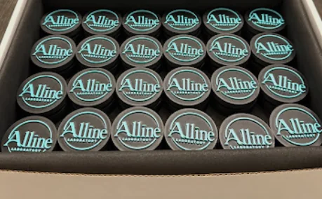Rows of charcoal clickers with teal logos packed in a shipping box
